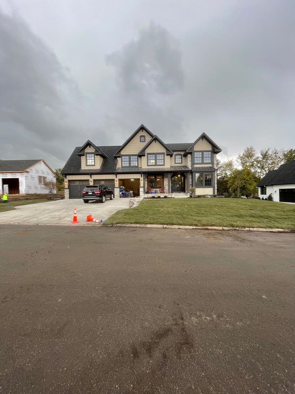 Modern two-story house with gray exterior and large windows, set on a manicured lawn.