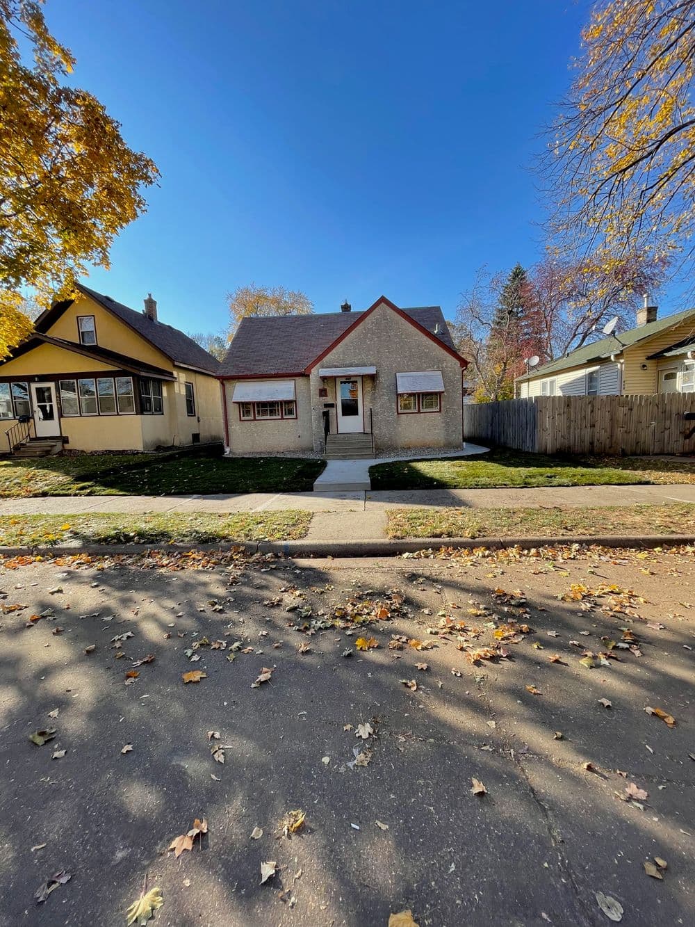 Charming single-story home with a landscaped yard and blue sky background in autumn.