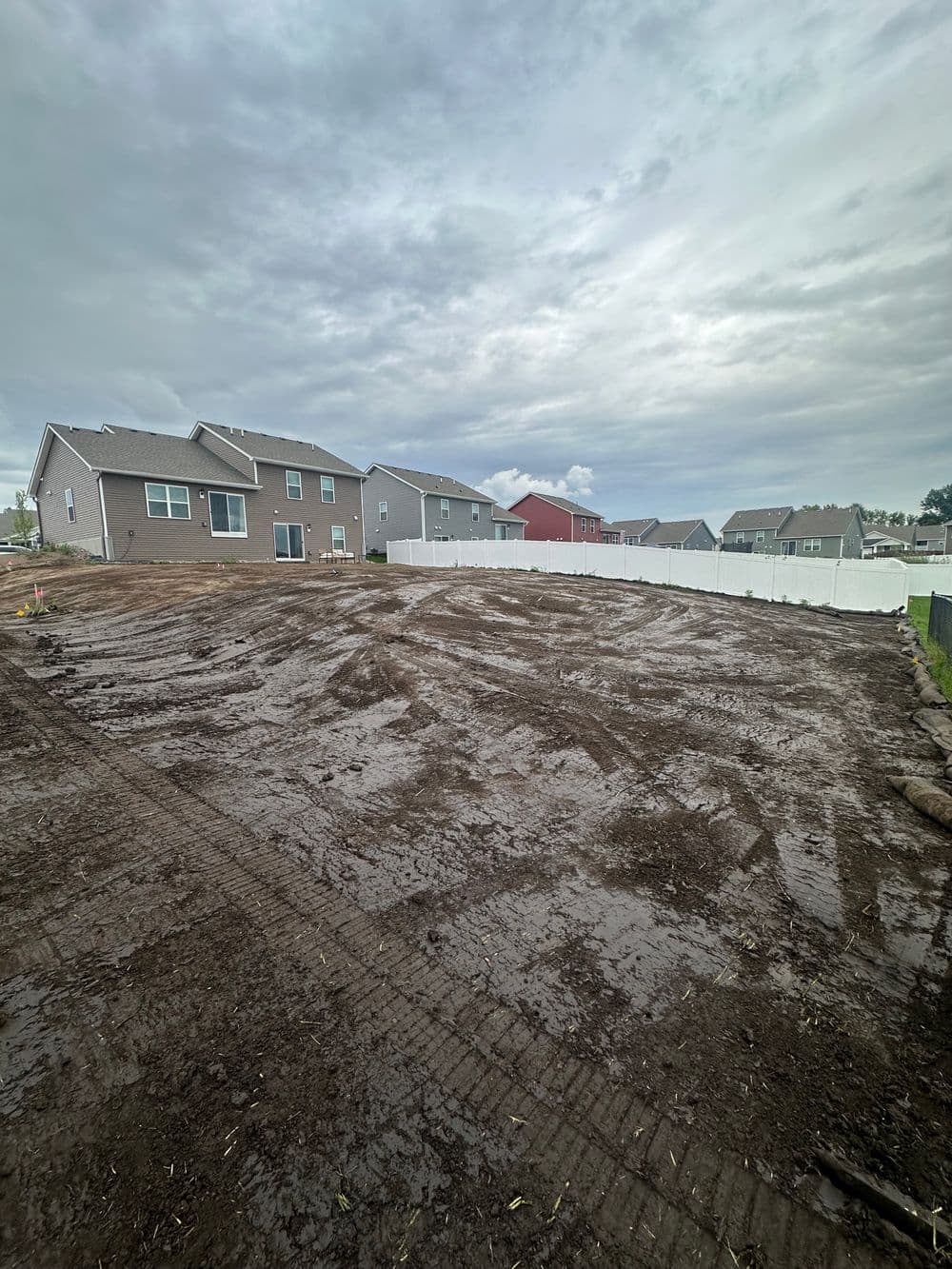 Gravel-covered yard with new construction homes and cloudy sky in the background.